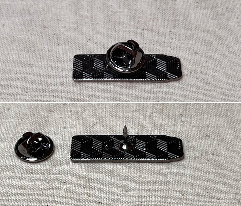 K&ouml;nnte beinhalten: Eine schwarze Metallstifte mit einem geometrischen Muster. Der Stift hat einen Sicherheitsverschluss auf der R&uuml;ckseite.
