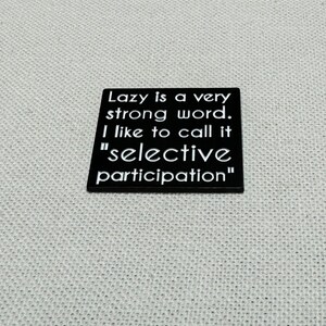 May include: Black square sign with white text that reads "Lazy is a very strong word. I like to call it "selective participation""