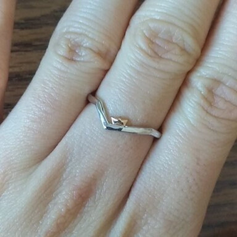 May include: A silver V-shaped ring with a small gold accent at the point of the V.