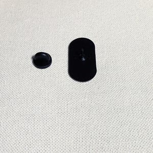 Op de afbeelding: Twee zwarte metalen pinruggen voor een speld of badge. De grotere pinrug is ovaalvormig en de kleinere is rond.