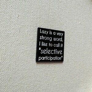 May include: Black square sign with white text that reads "Lazy is a very strong word. I like to call it "selective participation""