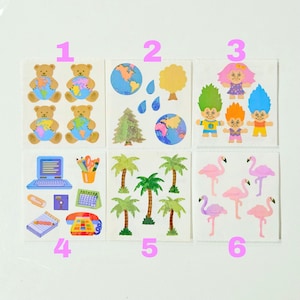 May include: A collection of six sticker sheets featuring various designs: teddy bears holding globes, nature elements like trees and raindrops, colorful troll figures, office supplies including a laptop and phone, palm trees, and pink flamingos.