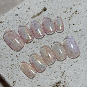 Könnte beinhalten: Set mit zehn ovalen, transparenten, regenbogenfarbenen pinkfarbenen Press-on-Nägeln mit Glitzer.
