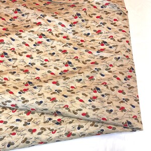 May include: Beige fabric with a repeating pattern of brown, red, and blue stylized shapes. The shapes resemble a bird or a leaf.