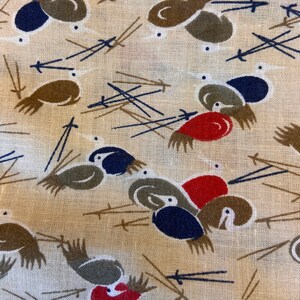 May include: A beige fabric with a repeating pattern of stylized birds. The birds are brown, red, blue, and white. The background is a light beige color.