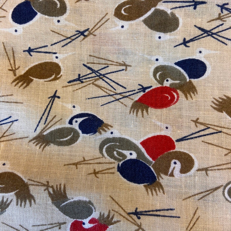 May include: A beige fabric with a repeating pattern of stylized birds. The birds are brown, red, blue, and white. The background is a light beige color.