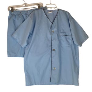 May include: A light blue pajama set with short sleeves and shorts. The top has a button-up front and a black trim around the collar and pockets.