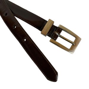 May include: A white ceramic mug with a black handle and the text "But First, Coffee" in a black, bold font. The mug is on a white surface.