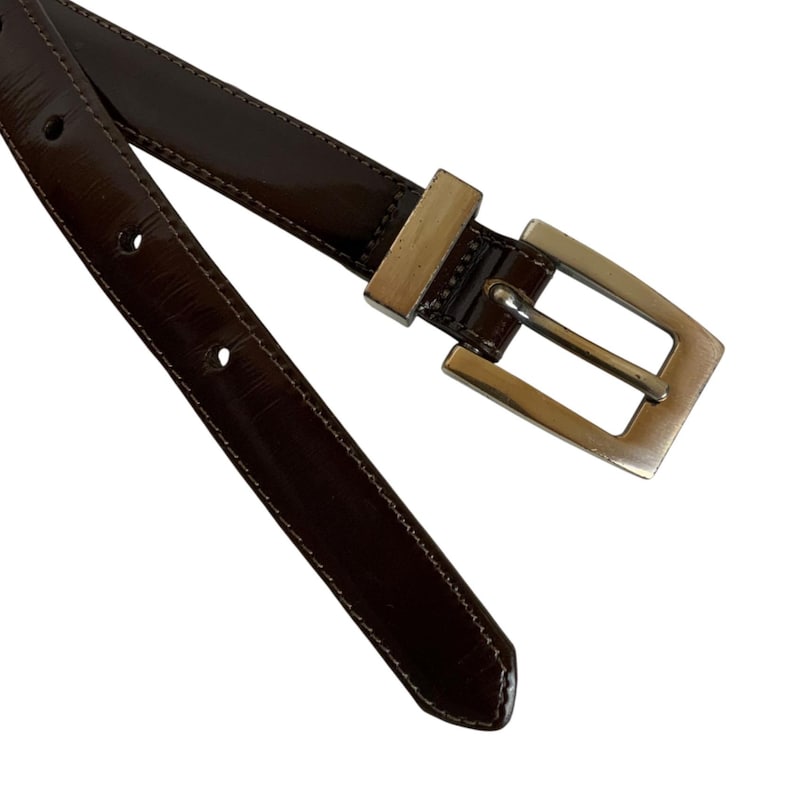 May include: A white ceramic mug with a black handle and the text "But First, Coffee" in a black, bold font. The mug is on a white surface.