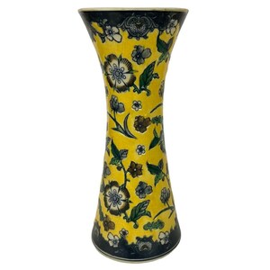 May include: A yellow ceramic vase with a floral pattern in shades of blue, green, and brown. The vase has a narrow neck and a wide base.