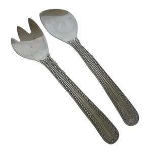 May include: A silver salad serving set, including a fork and spoon. The handles have a detailed beaded design. The fork has three tines. The spoon has a rounded bowl. The set is likely made of stainless steel.