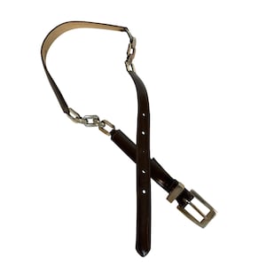 May include: A dark brown belt with a silver chain detail and a silver buckle. The belt is made of a smooth, shiny material and has several holes for adjustment. The chain is made of interlocking rectangular links.