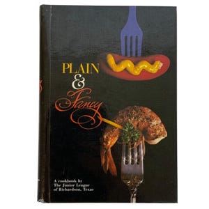 以下が含まれることがあります： 黒い表紙の「PLAIN & Fancy」というタイトルの料理本。表紙には、マスタードを添えたホットドッグとフォークに乗ったエビが描かれています。「A cookbook by The Junior League of Richardson, Texas」というテキストが下部にあります。