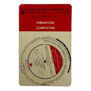 Könnte beinhalten: Ein weißer kreisförmiger Rechenschieber mit roten und schwarzen Markierungen. Der Rechenschieber ist mit "Vibration Computer" beschriftet und hat Skalen für Verschiebung, Geschwindigkeit, Beschleunigung und Frequenz. Der Rechenschieber wurde von Columbia Research Laboratories, Inc. in Woodlyn, PA hergestellt.