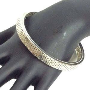 May include: A silver bangle bracelet with a dotted pattern.