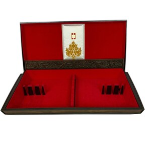 May include: Open wooden box with a red velvet interior. The box has a decorative gold and white panel on the inside of the lid. The box has slots and dividers for storage. The exterior is a dark brown color.