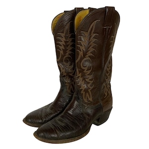 May include: A pair of brown leather cowboy boots. The boots have decorative stitching in a lighter brown color. The boots have pointed toes and a stacked heel. The interior of the boots is yellow.