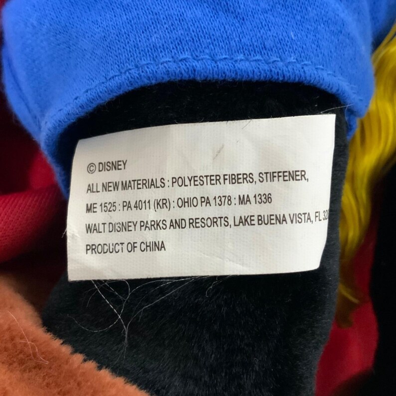 Peut inclure: Une &eacute;tiquette blanche avec du texte noir qui indique "&copy;DISNEY ALL NEW MATERIALS: POLYESTER FIBERS, STIFFENER, ME 1525: PA 4011 (KR): OHIO PA 1378: MA 1336 WALT DISNEY PARKS AND RESORTS, LAKE BUENA VISTA, FL 32 PRODUCT OF CHINA"