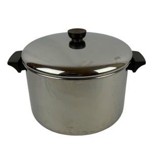 May include: A stainless steel stockpot with a polished finish, featuring two black side handles and a matching lid with a black knob. The cylindrical pot has a flat base and a smooth, reflective surface throughout its exterior body.
