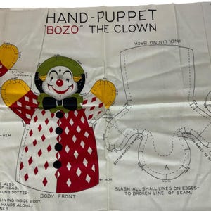 May include: A vintage sewing pattern for a hand puppet of Bozo the Clown. The pattern includes instructions for sewing the body, head, and arms. The pattern is printed on white fabric with black and red lines.
