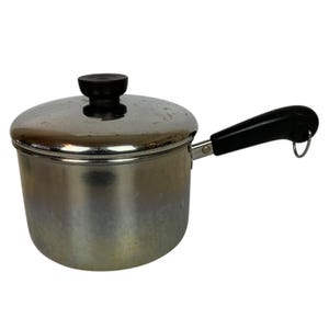 May include: A white ceramic mug with a black handle and the text "But First, Coffee" in a black, bold font. The mug is sitting on a white surface. The mug is approximately 4 inches tall.