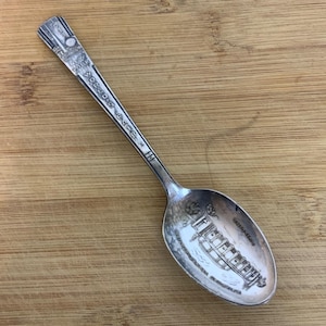 May include: A silver spoon with the text "New York World's Fair" engraved on the handle. The spoon's bowl features an engraved image of a boat and the text "Chicago".