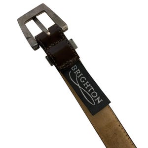 May include: A white ceramic mug with a black handle and the text "But First, Coffee" in a handwritten style. The mug is on a white surface. The mug is 4 inches tall.