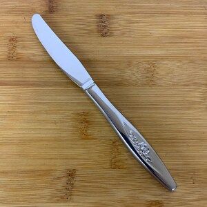 May include: A silver dinner knife with a floral design on the handle.