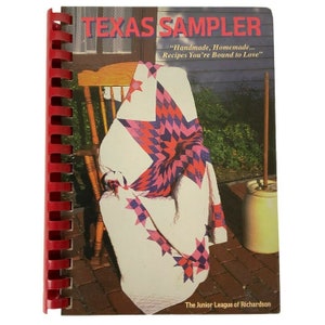 Könnte beinhalten: Ein rot gebundenes Kochbuch mit Spiralbindung mit dem Titel "Texas Sampler" und dem Slogan "Handmade, Homemade... Recipes You're Bound to Love" sowie einem Foto einer Steppdecke auf einem Schaukelstuhl auf dem Cover. Das Buch wurde von The Junior League of Richardson herausgegeben.