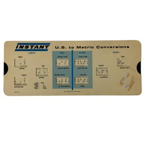 May include: A vintage, tan-colored, plastic conversion chart with blue lettering and markings. The chart is labeled "Instant U.S. to Metric Conversions" and includes measurements for length, area, volume, and weight. The chart has a sliding scale for each measurement type.