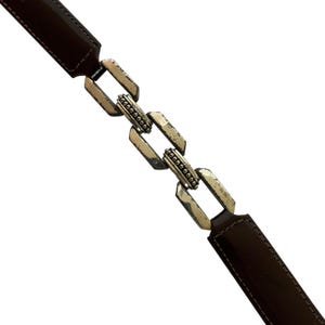 May include: A brown leather belt with a silver chain link design. The belt has a rectangular buckle and a series of interconnected links. The leather is a dark brown color, and the metal has a distressed finish.