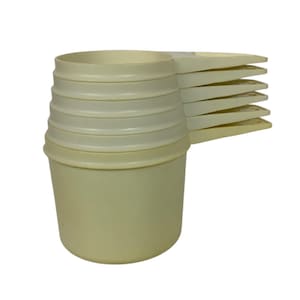 Può includere: Un set di sei misurini bianco sporco. Le tazze sono impilate, con manici che si estendono verso destra. Ogni tazza ha un corpo cilindrico e un bordo leggermente svasato. Il set è realizzato in materiale plastico resistente.