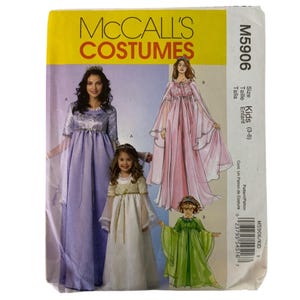 May include: McCall's Costumes pattern M5906 for kids' dresses. The pattern features illustrations of various medieval-style dresses in lavender, pink, white, and green. The size range is for kids aged 3-8.