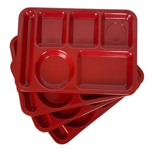 May include: A stack of red plastic lunch trays. Each tray has six compartments of various shapes and sizes, including a circular section for a drink. The trays are made of a glossy, durable plastic.