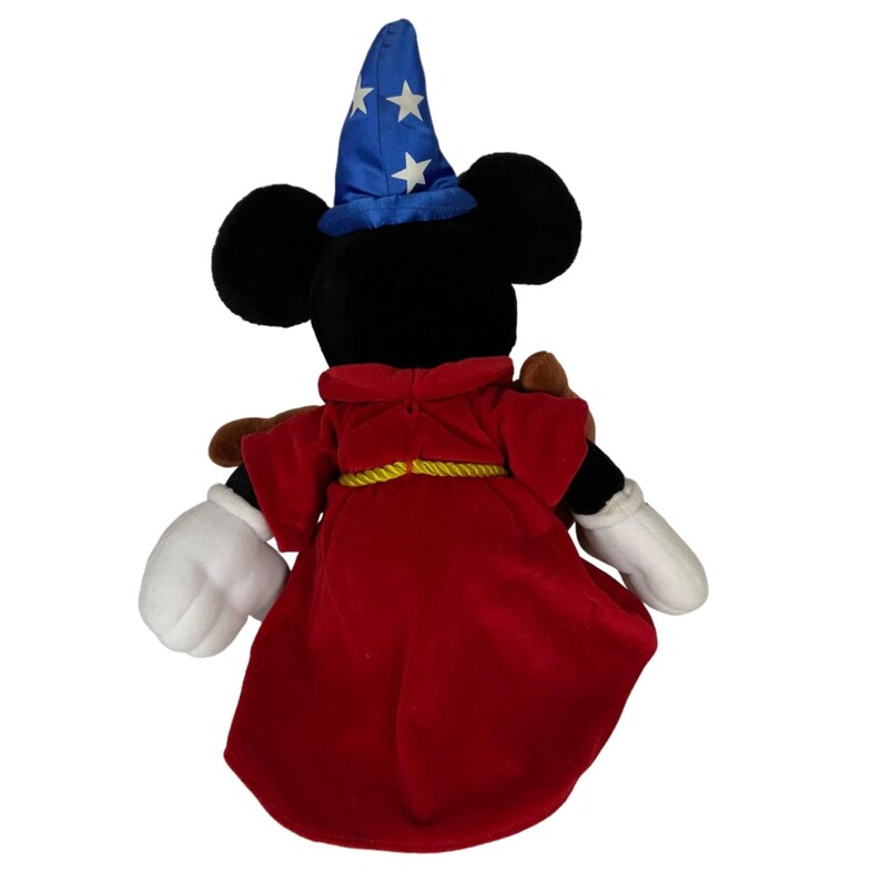 Peut inclure: Un Mickey Mouse en peluche habill&eacute; en sorcier. Il porte une robe rouge avec une ceinture en corde dor&eacute;e, un chapeau bleu avec des &eacute;toiles blanches et des gants blancs.