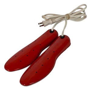 Puede incluir: Un par de secadores de zapatos rojos con un cable de alimentación y un enchufe blancos. Los secadores de zapatos tienen forma de plantillas y tienen varios pequeños orificios de ventilación negros. El cable está agrupado con una goma elástica.
