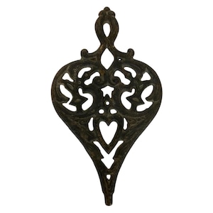 May include: A decorative metal heart-shaped ornament with intricate cut-out designs. The ornament is dark brown and has a pointed bottom.