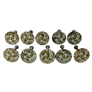 May include: Ten white ceramic cabinet knobs with a gold swirl design.