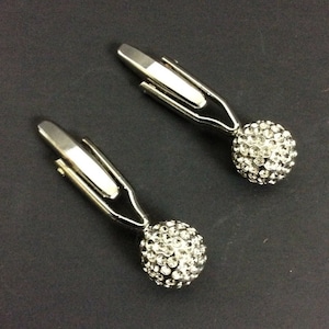 May include: A pair of silver cufflinks with a round, clear crystal design. Each cufflink has a silver clasp.