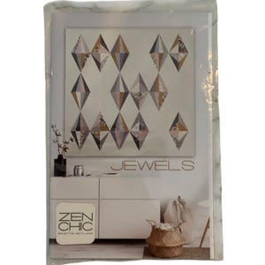 May include: A packaged quilt pattern titled "JEWELS" by Zen Chic. The pattern features a geometric design of diamond shapes in shades of brown, gray, and cream. The package includes a photo of the finished quilt and the Zen Chic logo.
