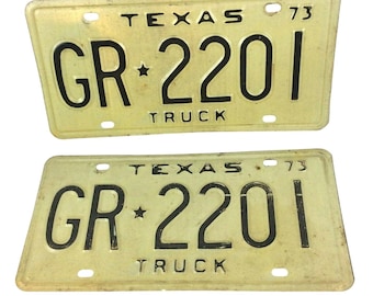 May include: Two vintage yellow Texas license plates with black lettering. The plates read "Texas 73 GR*2201 TRUCK".
