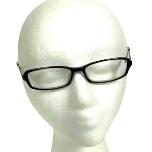 May include: Black rectangular eyeglasses with a slightly curved design. The frames are solid black, and the lenses are clear. The glasses are displayed on a white foam head, highlighting their shape and style.