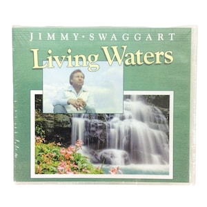 May include: A green and white cassette tape case with the title "Living Waters" and the name "Jimmy Swaggart" printed on the front. The case features a photo of a man sitting in front of a waterfall.