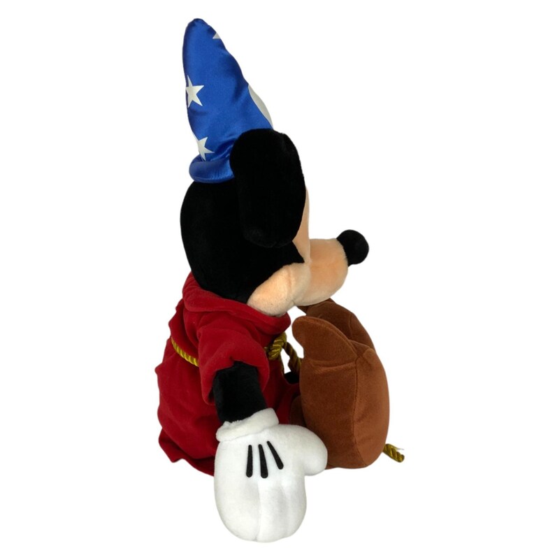 Peut inclure: Un jouet en peluche Mickey Mouse portant un chapeau de sorcier bleu avec des &eacute;toiles blanches. Il est v&ecirc;tu d'une robe rouge avec une ceinture en corde dor&eacute;e et porte des chaussures brunes.