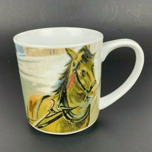 Op de afbeelding: Witte keramische mok met een gedetailleerde illustratie van een paard met tuig. Het paard is in tinten groen, bruin en geel, met een rood accent. De mok heeft een wit handvat en een witte binnenkant.