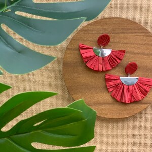 May include: A pair of red tassel earrings with silver accents. The earrings are fan-shaped and have a fringe-like design.