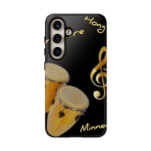 May include: Black phone case with a pair of conga drums and a golden treble clef design. The words "Hong" and "Minne" are written in gold script. The case has a glossy finish and a camera module.