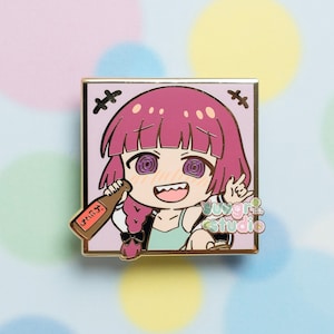 Puede incluir: Un pin de esmalte rosa y dorado con un personaje de dibujos animados con cabello rosa, una camisa verde y una botella de sake. El personaje tiene una amplia sonrisa y ojos en espiral. El pin está enmarcado en un cuadrado dorado con un borde negro y el texto "sugar studio" en la esquina inferior derecha.