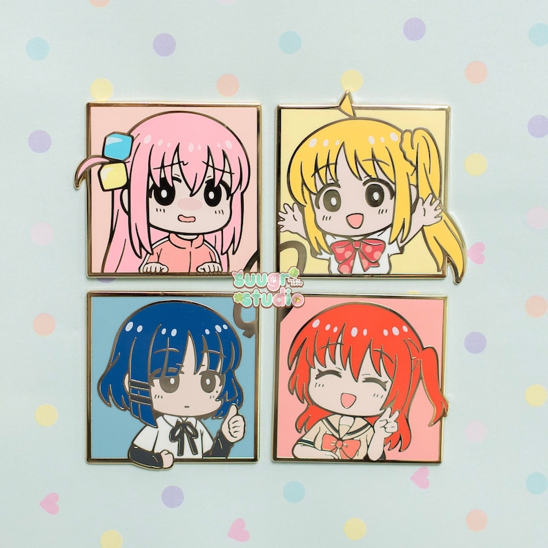 May include: Four enamel pins featuring cartoon characters with different coloured hair and outfits. The characters are all smiling and have large eyes. The pins are set against a light blue background with white polka dots.