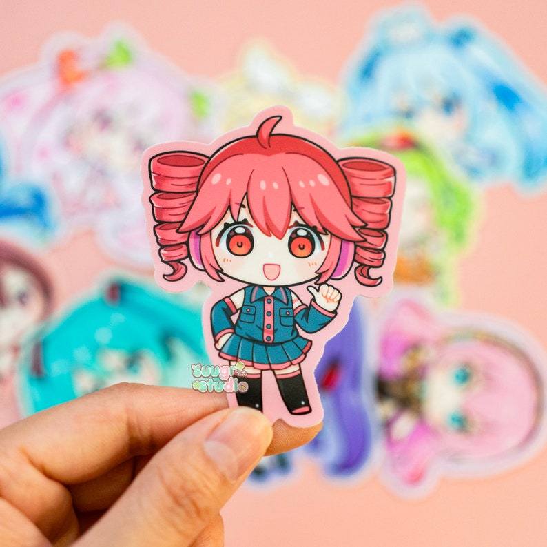 K&ouml;nnte beinhalten: Ein Aufkleber mit einer Comicfigur mit rosa Haaren, die ein blaues und schwarzes Outfit und Kopfh&ouml;rer tr&auml;gt. Die Figur l&auml;chelt und zeigt mit einer Hand. Der Aufkleber befindet sich auf einem rosa Hintergrund.